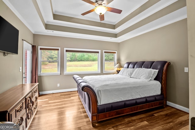 bedroom with ornamental molding, a tray ceiling, ceiling fan, and light hardwood / wood-style flooring