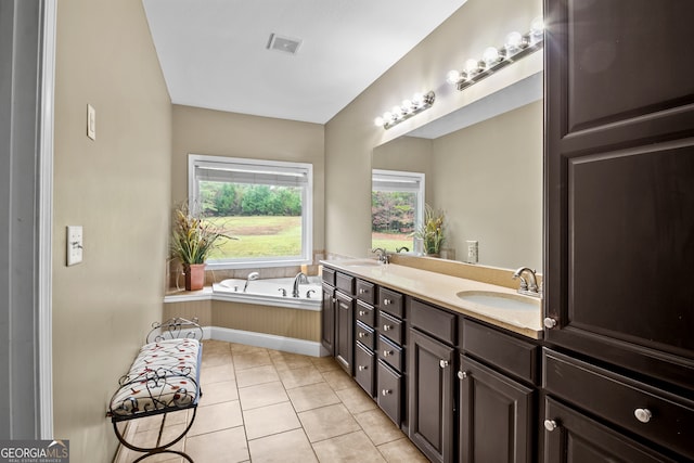 bathroom with vanity, tile patterned flooring, and tiled tub