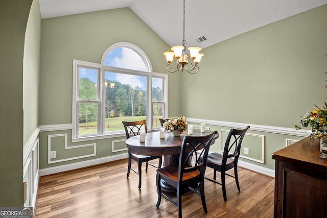 dining area featuring a chandelier, vaulted ceiling, and light hardwood / wood-style flooring