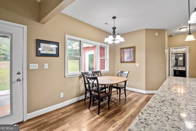 dining area featuring a wealth of natural light, a notable chandelier, and hardwood / wood-style flooring