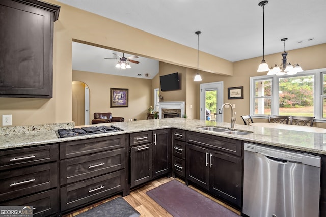 kitchen featuring a fireplace, stainless steel appliances, light wood-type flooring, pendant lighting, and sink