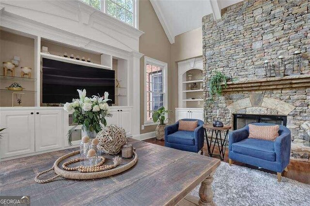 living room with beamed ceiling, built in features, a fireplace, high vaulted ceiling, and dark hardwood / wood-style flooring