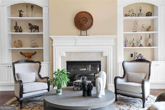 living area with a premium fireplace, dark hardwood / wood-style floors, and built in shelves