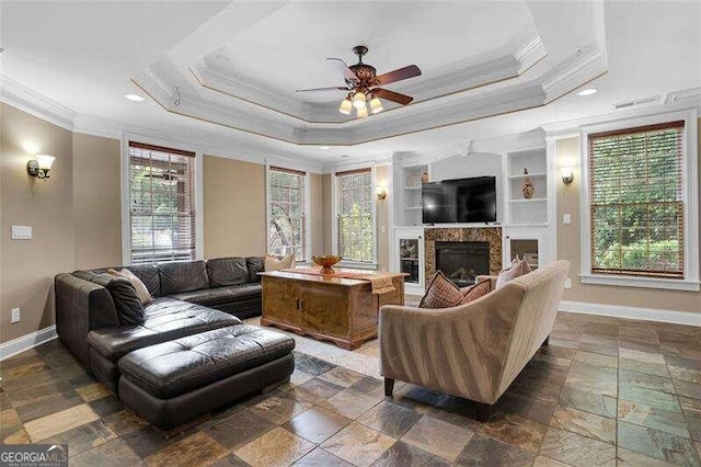 living room with a raised ceiling, a wealth of natural light, and built in shelves