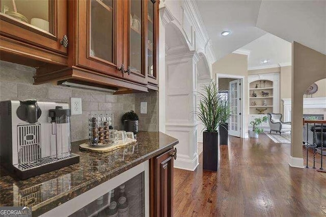 kitchen with tasteful backsplash, dark stone countertops, ornamental molding, dark hardwood / wood-style floors, and built in shelves