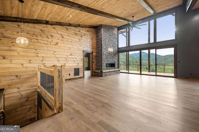 unfurnished living room with beam ceiling, a mountain view, wood-type flooring, wooden ceiling, and a fireplace