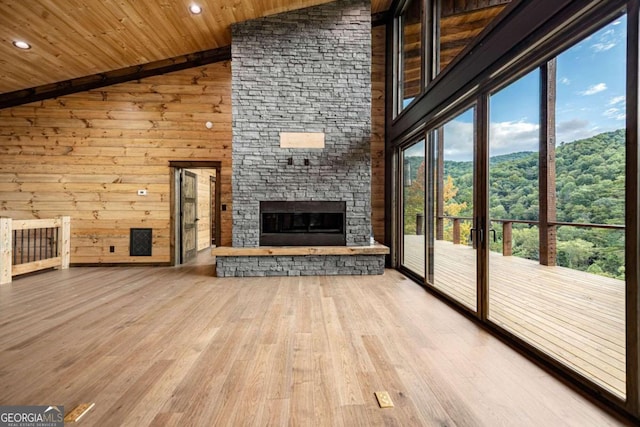 unfurnished living room with hardwood / wood-style flooring, high vaulted ceiling, wooden ceiling, wood walls, and a fireplace