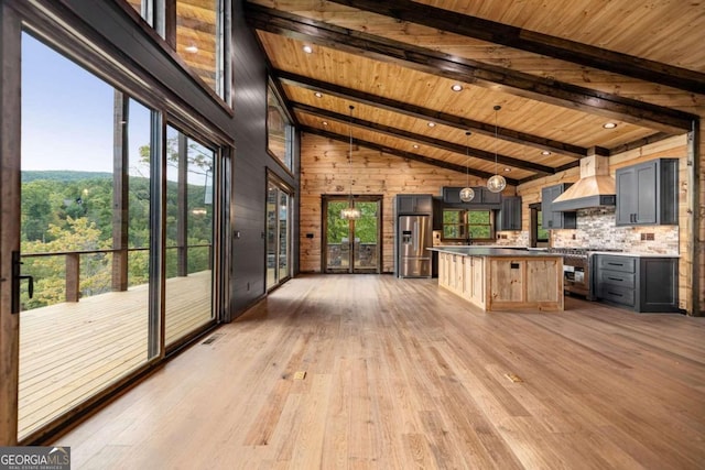 kitchen with wood ceiling, hardwood / wood-style floors, wood walls, custom range hood, and stainless steel appliances