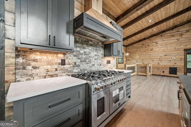 kitchen with wall chimney range hood, vaulted ceiling with beams, double oven range, light hardwood / wood-style floors, and wood walls