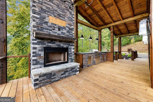 deck with an outdoor stone fireplace, grilling area, and an outdoor kitchen