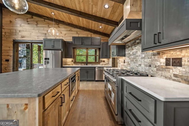 kitchen featuring hanging light fixtures, vaulted ceiling, light hardwood / wood-style flooring, wood walls, and high quality appliances