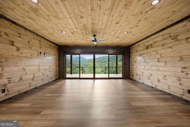 spare room featuring ceiling fan, wood walls, wood-type flooring, and wooden ceiling