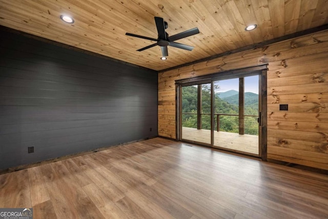 spare room featuring light hardwood / wood-style flooring, wood walls, a mountain view, and wooden ceiling