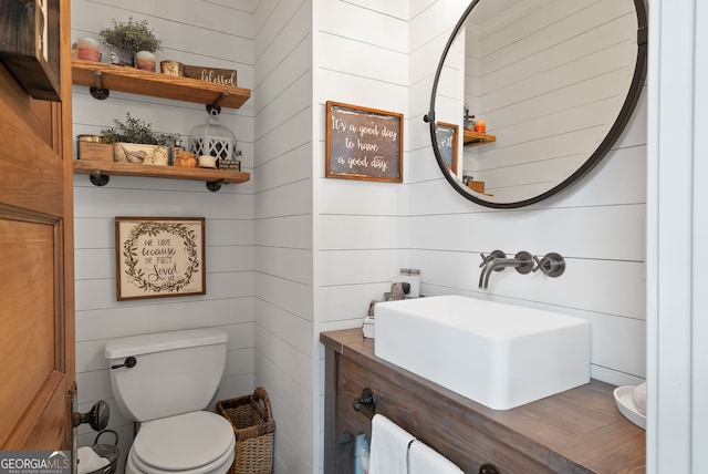 bathroom featuring vanity, toilet, and wood walls