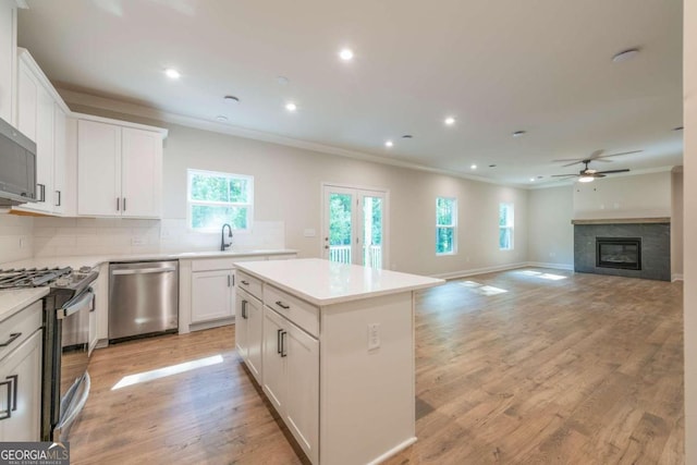 134 Henley St W Unit 09, Canton, GA 30114 - kitchen featuring appliances with stainless steel finishes, ornamental molding, a ceiling fan, a center island, and tasteful backsplash