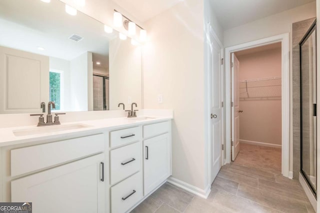 134 Henley St W Unit 09, Canton, GA 30114 - bathroom with a shower stall, double vanity, a walk in closet, baseboards, and tile patterned flooring