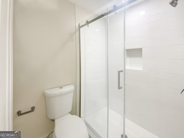 bathroom with a shower with door and toilet