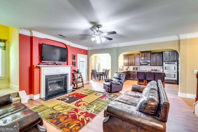 living room featuring ceiling fan, crown molding, and light hardwood / wood-style flooring