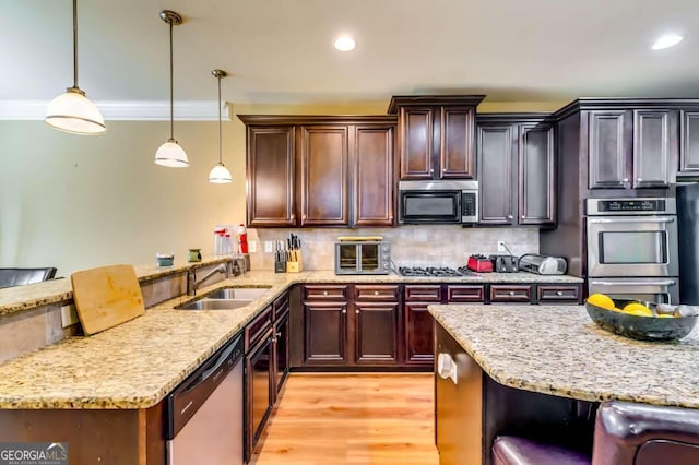 kitchen with appliances with stainless steel finishes, ornamental molding, hanging light fixtures, and a kitchen bar