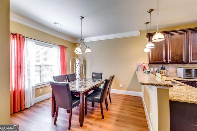 dining space featuring sink, crown molding, and light hardwood / wood-style flooring