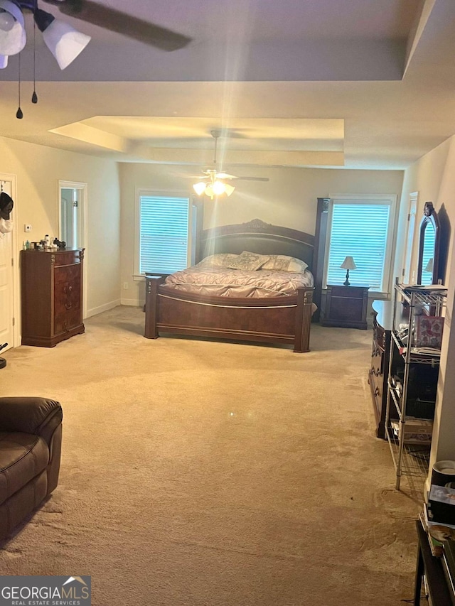 bedroom featuring carpet flooring, a tray ceiling, and ceiling fan