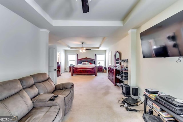 bedroom with light carpet, a tray ceiling, and ceiling fan