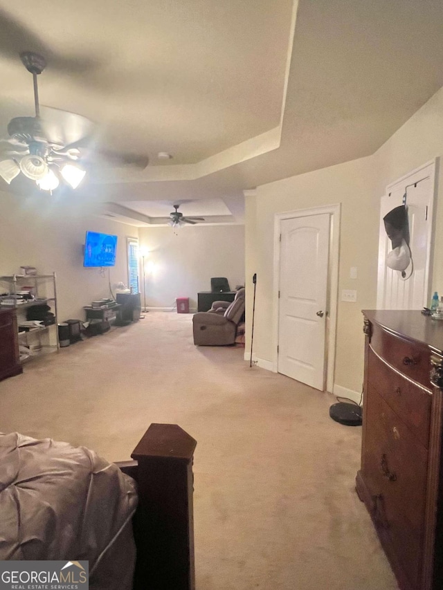 living room featuring a raised ceiling, light colored carpet, and ceiling fan