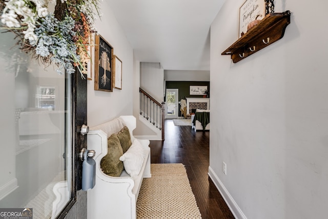 foyer featuring dark wood-type flooring and a brick fireplace