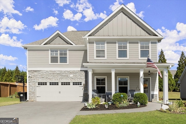 view of front facade with covered porch, a front yard, and a garage