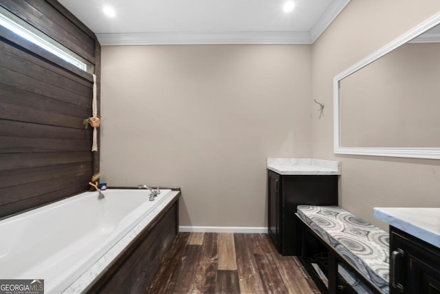 bathroom featuring vanity, crown molding, hardwood / wood-style flooring, and a tub to relax in