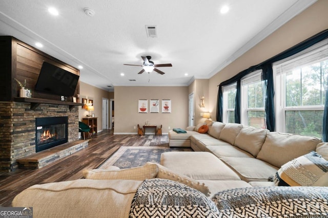 living room with a stone fireplace, crown molding, hardwood / wood-style flooring, and ceiling fan