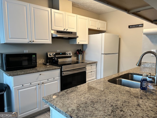 kitchen featuring light stone counters, white cabinetry, white fridge, and stainless steel range with electric cooktop