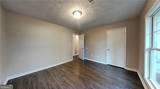 unfurnished bedroom with a textured ceiling and dark wood-type flooring