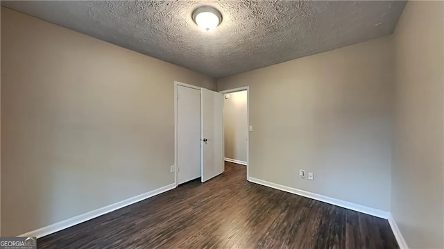 unfurnished bedroom with a textured ceiling and dark hardwood / wood-style floors