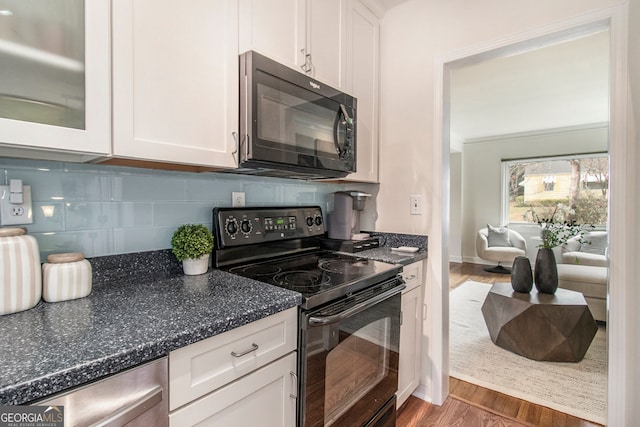 kitchen with black appliances, white cabinetry, decorative backsplash, and dark hardwood / wood-style floors