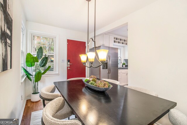 dining area with an inviting chandelier, sink, and hardwood / wood-style flooring