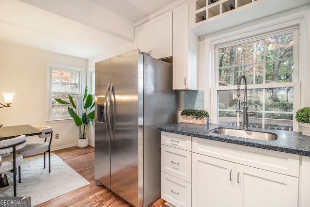 kitchen with sink, stainless steel fridge with ice dispenser, backsplash, white cabinetry, and light wood-type flooring