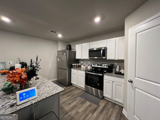 kitchen featuring appliances with stainless steel finishes, white cabinetry, light stone countertops, and dark hardwood / wood-style flooring