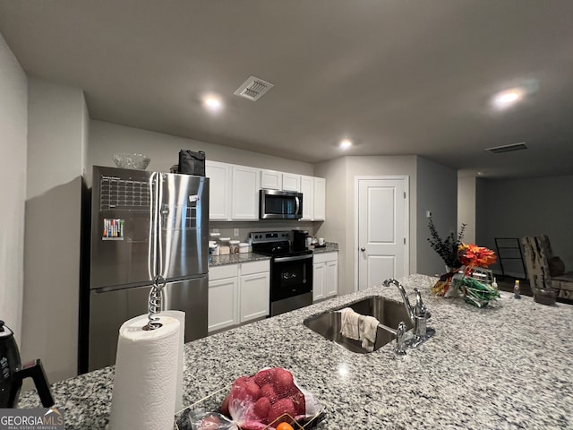 kitchen featuring white cabinetry, stainless steel appliances, light stone countertops, and sink