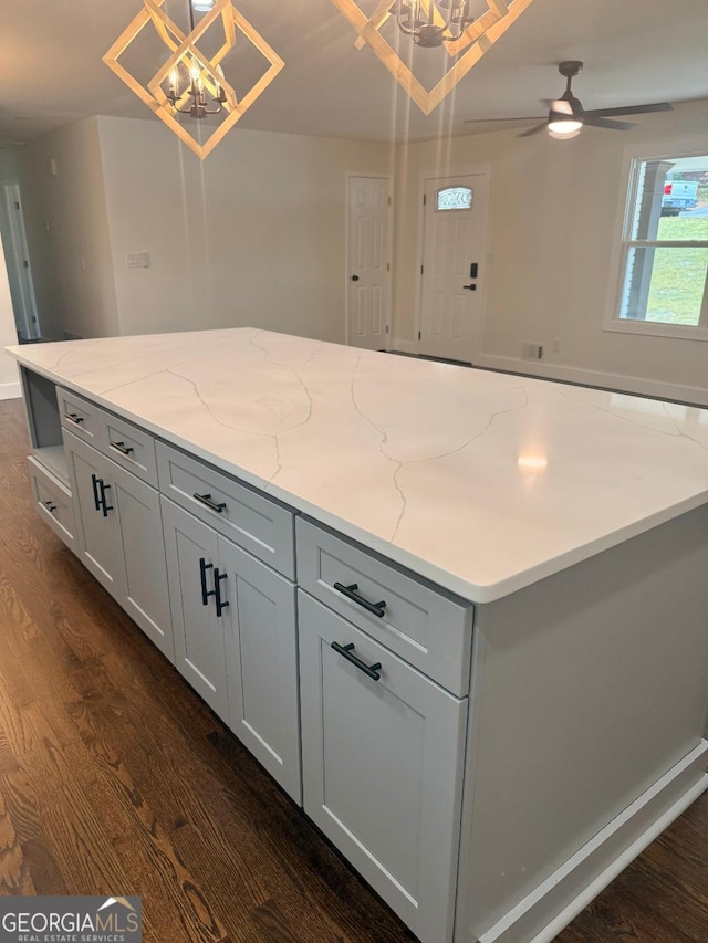 kitchen featuring decorative light fixtures, light stone counters, and dark wood-type flooring