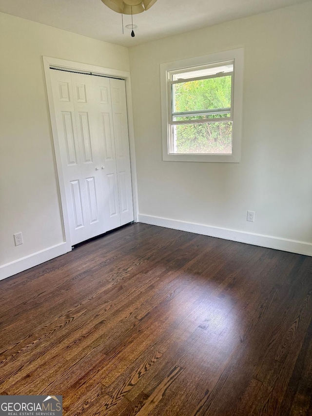 unfurnished bedroom featuring a closet and dark hardwood / wood-style flooring