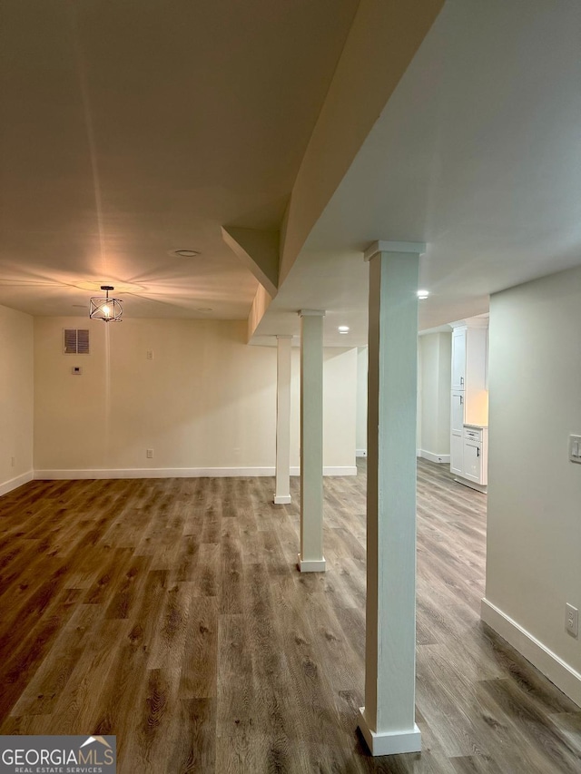 finished basement featuring baseboards, visible vents, and wood finished floors