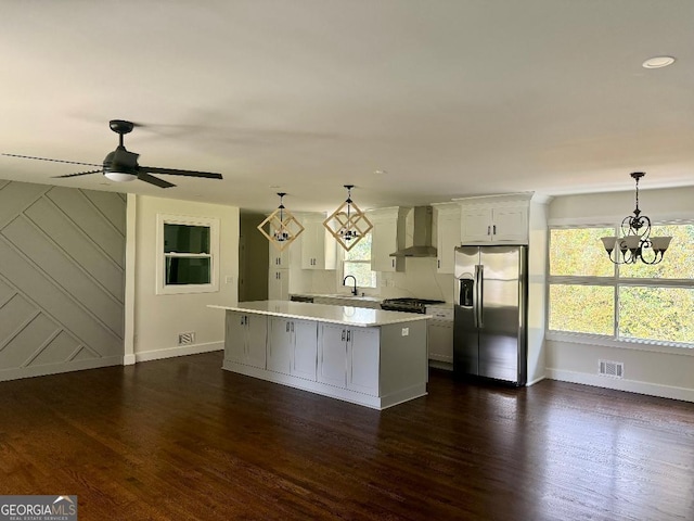 kitchen with white cabinets, appliances with stainless steel finishes, dark hardwood / wood-style floors, wall chimney exhaust hood, and decorative light fixtures