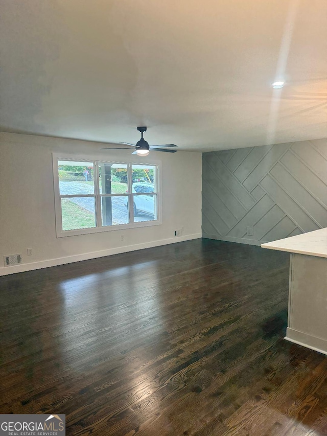 unfurnished living room with dark wood-type flooring and ceiling fan