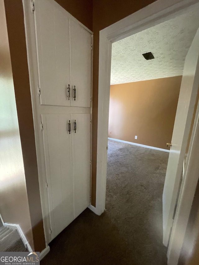 8596 Creekwood Way, Jonesboro, GA 30238 - hallway with dark colored carpet, baseboards, and a textured ceiling