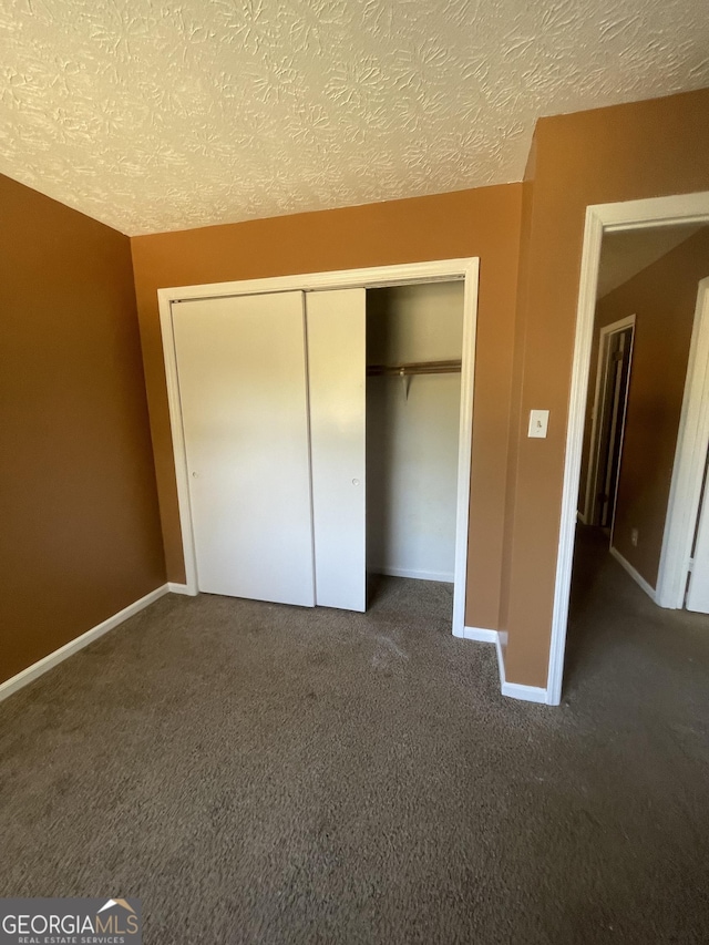 8596 Creekwood Way, Jonesboro, GA 30238 - unfurnished bedroom with a closet, carpet floors, a textured ceiling, and baseboards