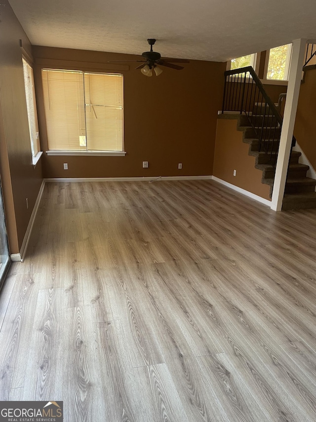 8596 Creekwood Way, Jonesboro, GA 30238 - unfurnished living room with wood finished floors, baseboards, a ceiling fan, and stairs