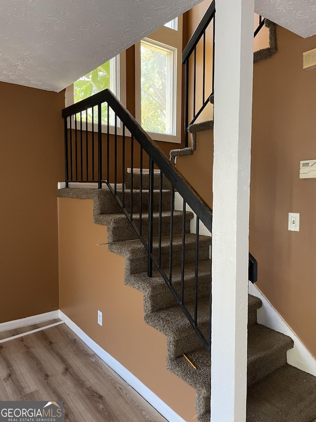 8596 Creekwood Way, Jonesboro, GA 30238 - stairs featuring wood finished floors, a textured ceiling, and baseboards