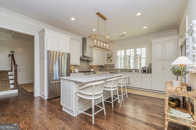 kitchen with high end fridge, a center island, wall chimney exhaust hood, white cabinets, and dark wood-type flooring