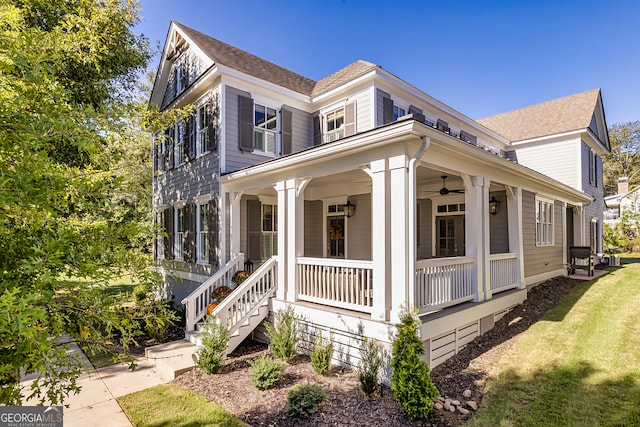 view of side of property with ceiling fan, a porch, and a lawn